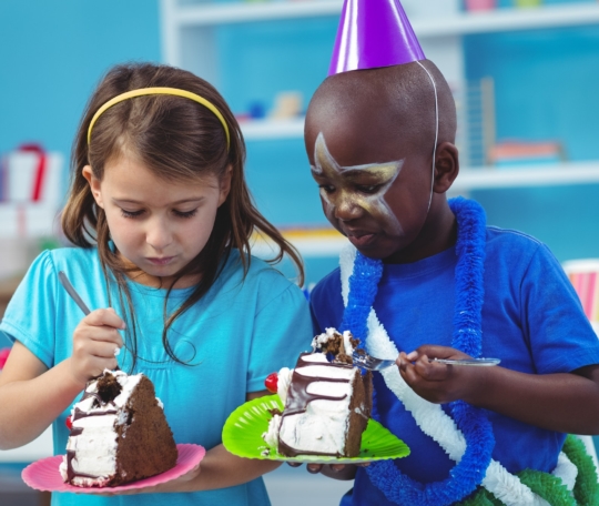 Happy kids eating birthday cake at the party